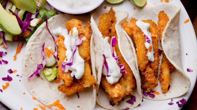 A selection of crispy fish tacos, smothered in white sauce and cabbage