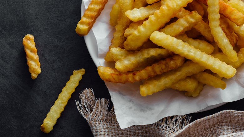 A pile of crispy crinkle-cut fries sits on a napkin