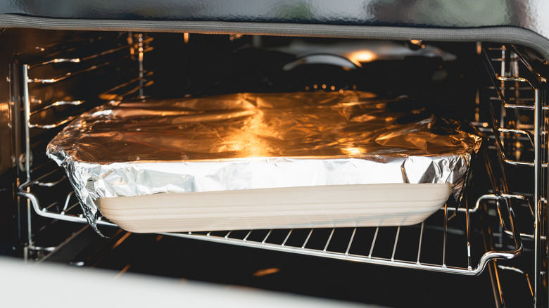 Foil covered casserole dish in oven