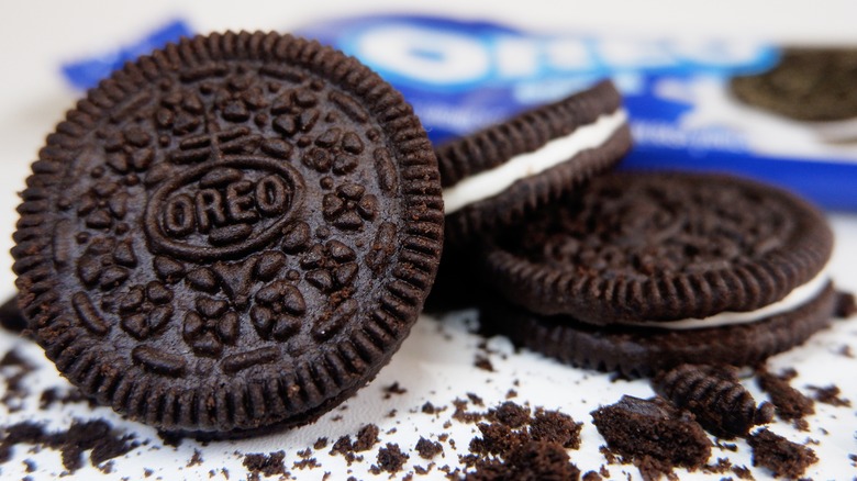 Oreo cookies and crumbles on a white surface