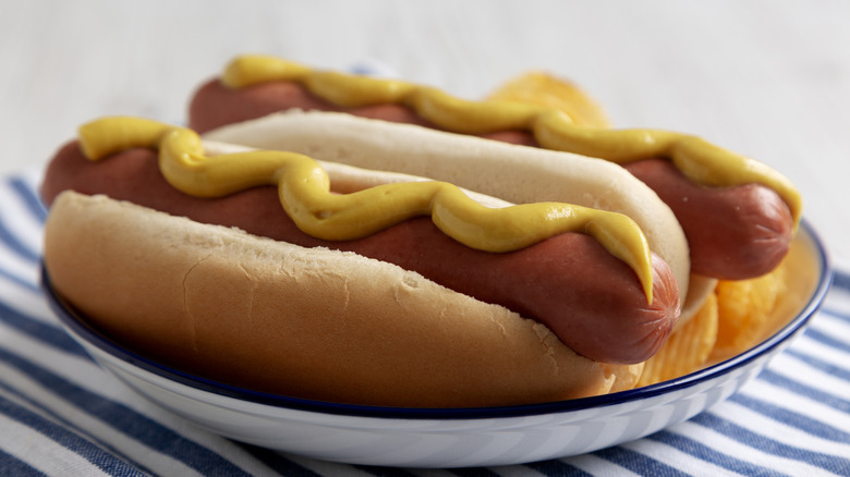 Two classic American hot dogs with a drizzle of mustard.