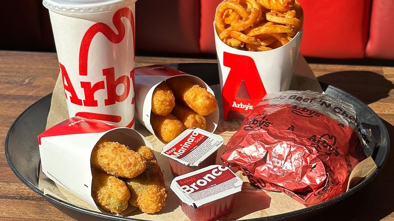 Various Arby's sides pictured with a drink and sandwich.