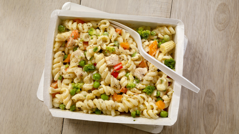 A frozen portion of pasta primavera has been heated up and has a fork in it