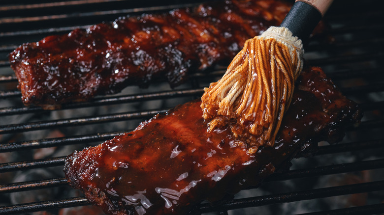Ribs being smothered in barbecue sauce