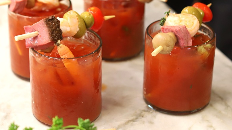 Bloody marys garnished with olives, tomatoes, cheeses, and meats