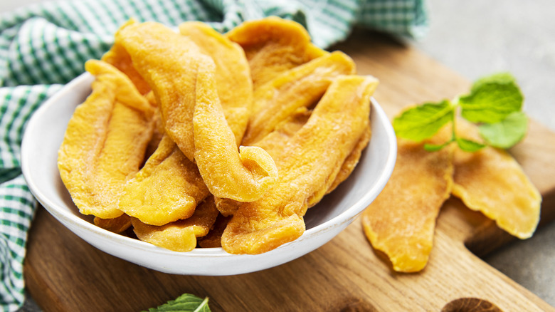 Dried mango in a bowl on a wooden platter