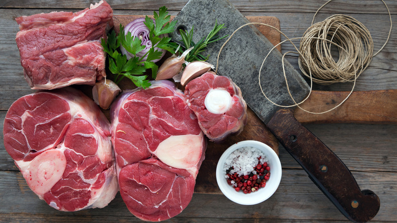 Different cuts of beef on a wooden board with ingredients