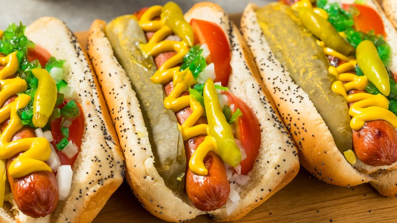 Three Chicago hot dogs in a row on a table