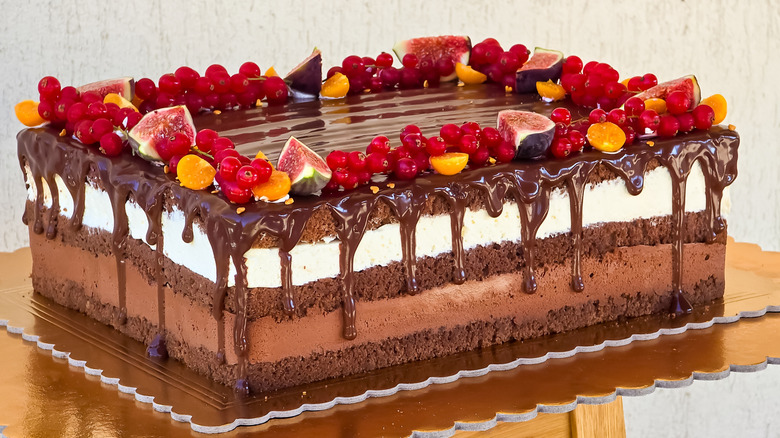 A chocolate layer cake topped with berries and figs