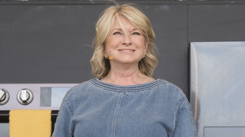 Martha Stewart wearing a denim top, standing in a kitchen with oven in background