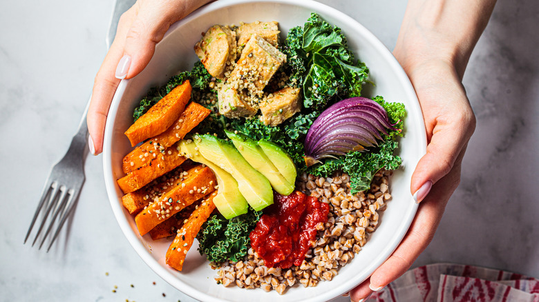 buddha bowl featuring kale, avocado, sweet potato, red onion