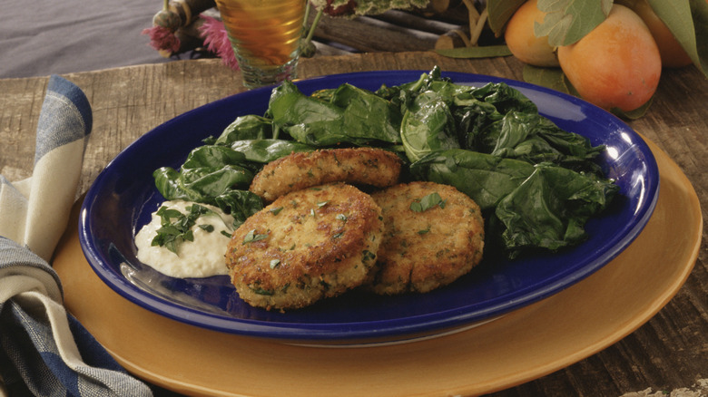 Southern style crab cakes on a bed of fresh greens with a side of remoulade sauce