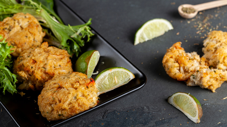 Maryland style crab cakes with lime wedges and fresh lettuce