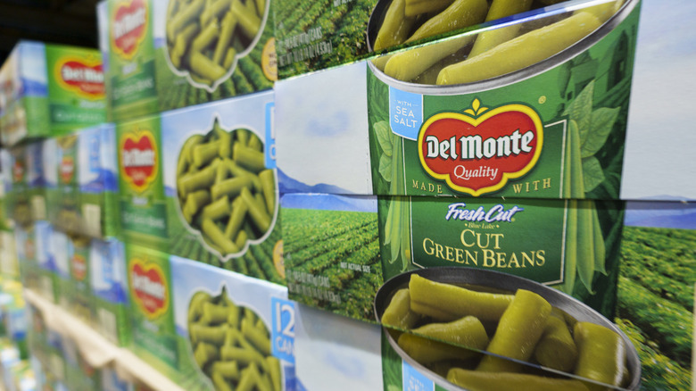 Cans of Del Monte cut green beans on a store shelf