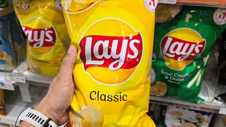 Bag of Lay's Classic potato chips held by a customer's hand at store