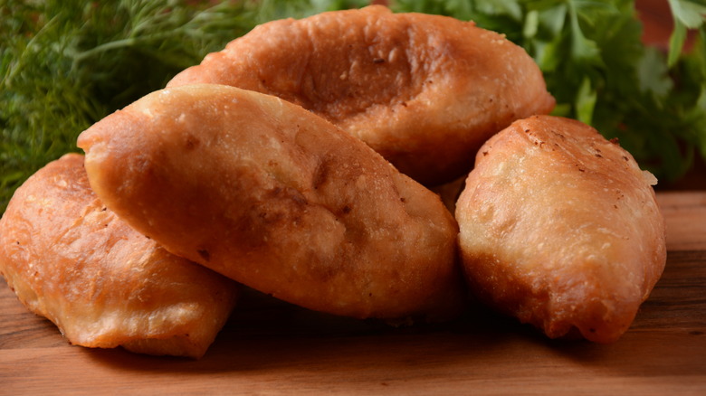 Crispy pirozhki served on a wooden board