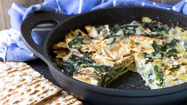 Matzo brei with spinach and onion sits in a cast iron skillet