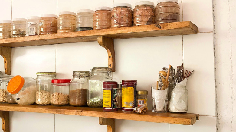 Jars with dry goods on wooden floating shelves.