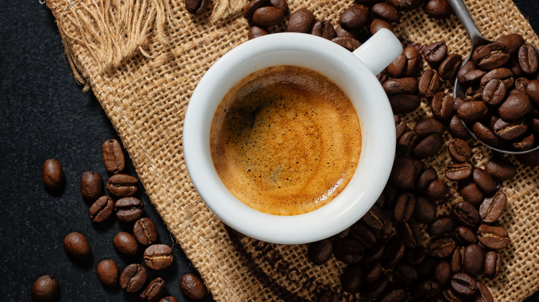 A cup of espresso over espresso beans