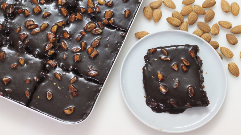 A sliced Texas sheet cake surrounded by almonds