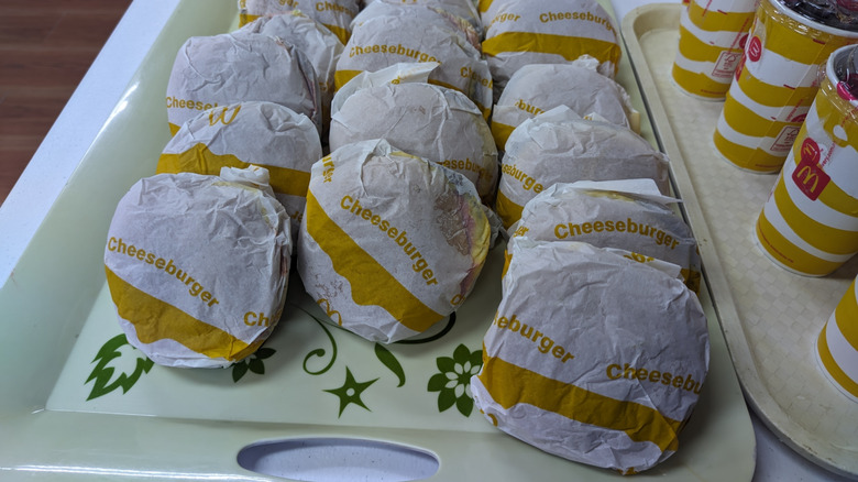 Many McDonald's cheeseburgers sit on a tray.