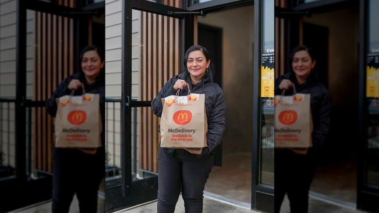 A woman holds a bag that reads "McDelivery"
