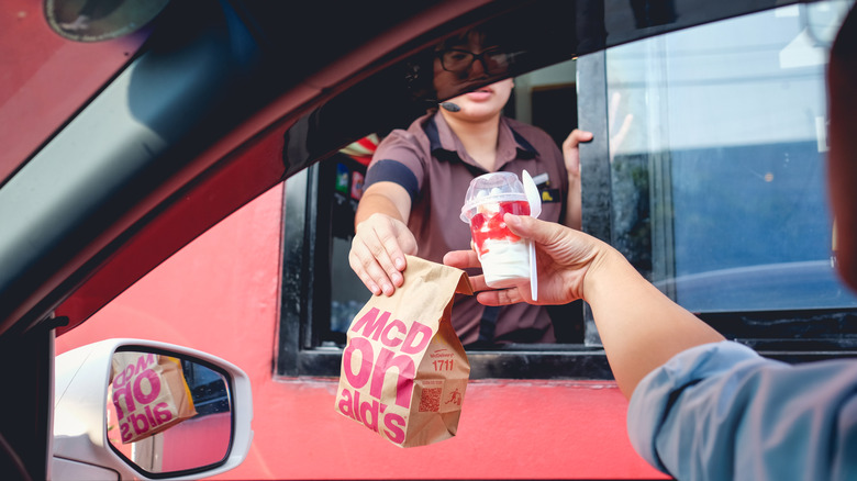 A customer in a vehicle receives their order at a McDonald's drive-thru