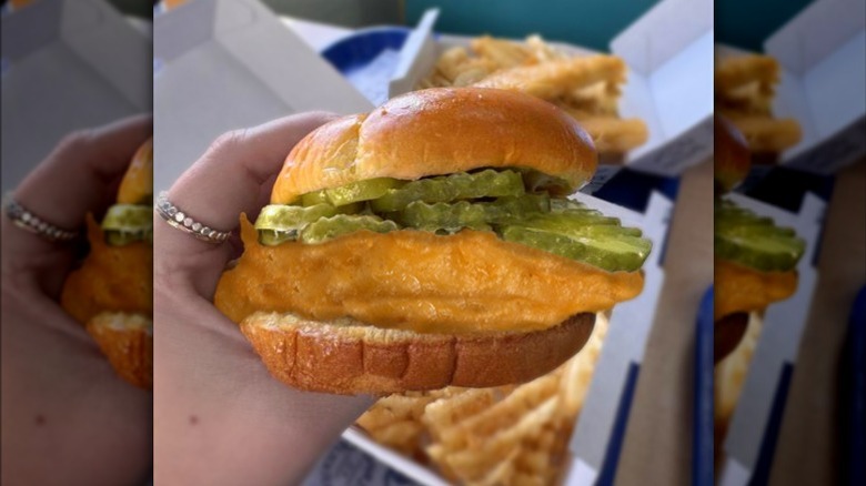 A hand holds up a Long John Silver's Fish Sandwich