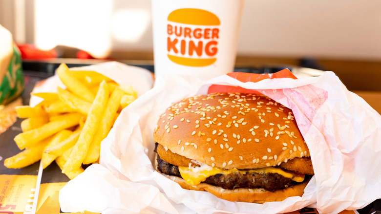 A tray of Burger King food, including a partially unwrapped burger, fries, and a drink