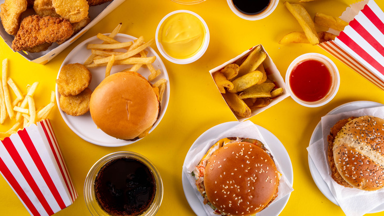 Various fast food burgers, nuggets, and fries on a yellow background