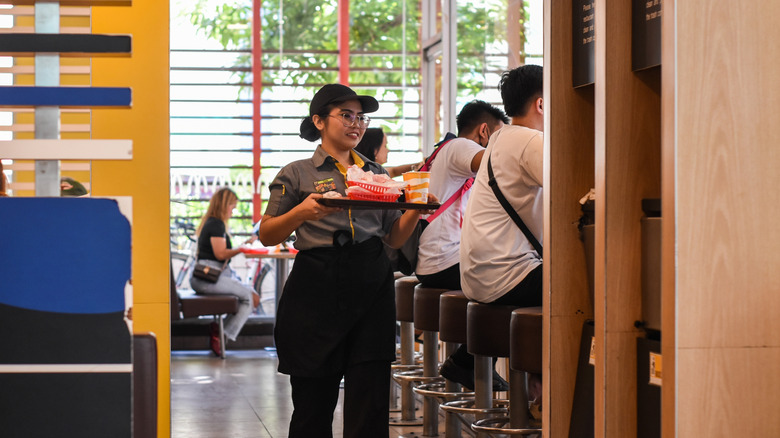 A McDonald's employee holds a tray of food