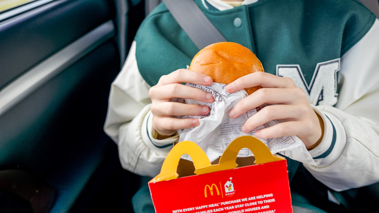 A teenager holds a burger in his hands.