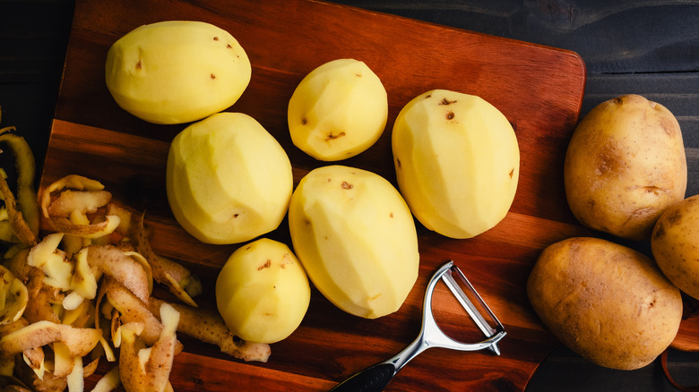 Yukon Gold potatoes on a cutting board with a vegetable peeler