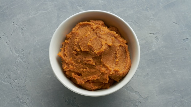Small white bowl of reddish miso against gray background