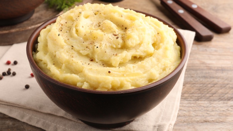 Brown bowl of mashed potatoes with black pepper
