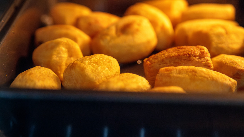 Closeup of a tray of roasting potatoes inside a hot oven