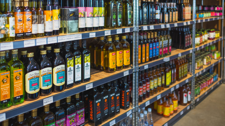 Rows of different types of cooking oil are displayed on supermarket shelves