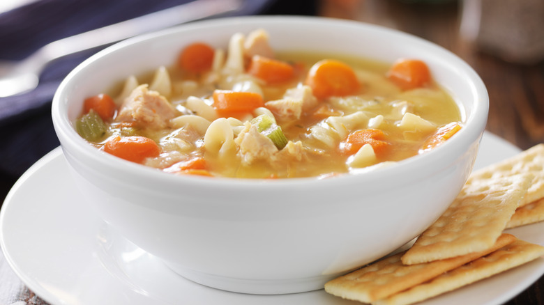 Bowl of chicken noodle soup with crackers