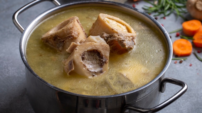 three bones in broth with sliced carrots on counter