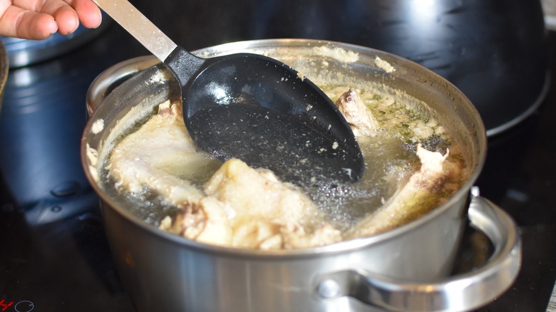 black and silver spoon skimming broth in silver pot