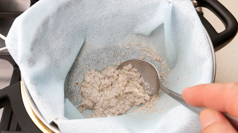 straining through cheesecloth, silver spoon, partial hand