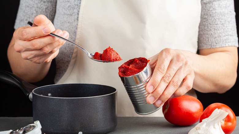 Canned tomatoes being added to pot