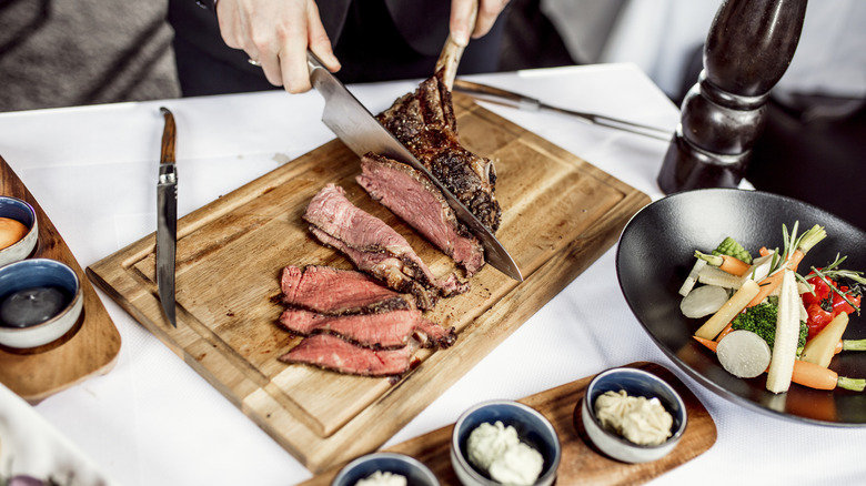 A hand slicing a large steak