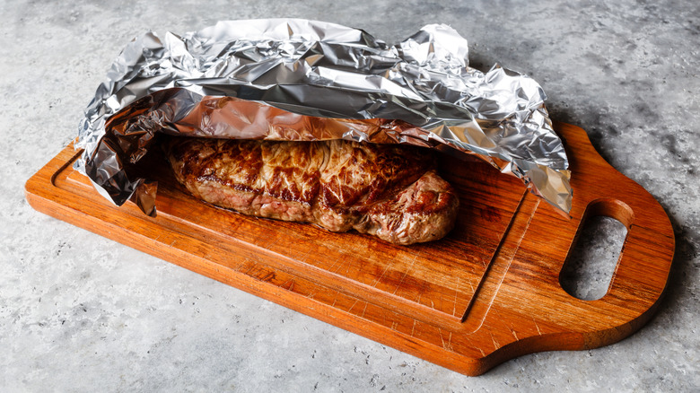 A steak resting with foil over it