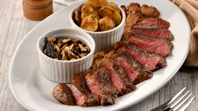 Steak sliced at an angle with potatoes and mushrooms