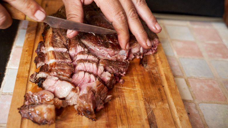 A hand chopping a steak
