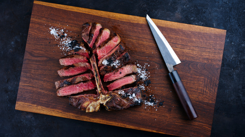 A sliced steak on a chopping board with a knife