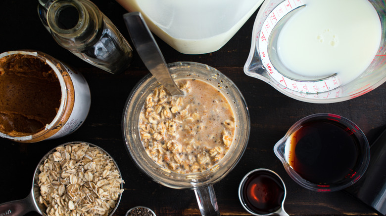 Overnight oats being mixed in a measuring cup surrounded by the wet ingredients