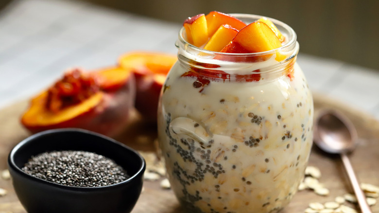 Overnight oats topped with peaches next to chia seeds and cut fruit