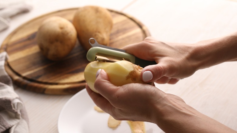 hands peeling a potato